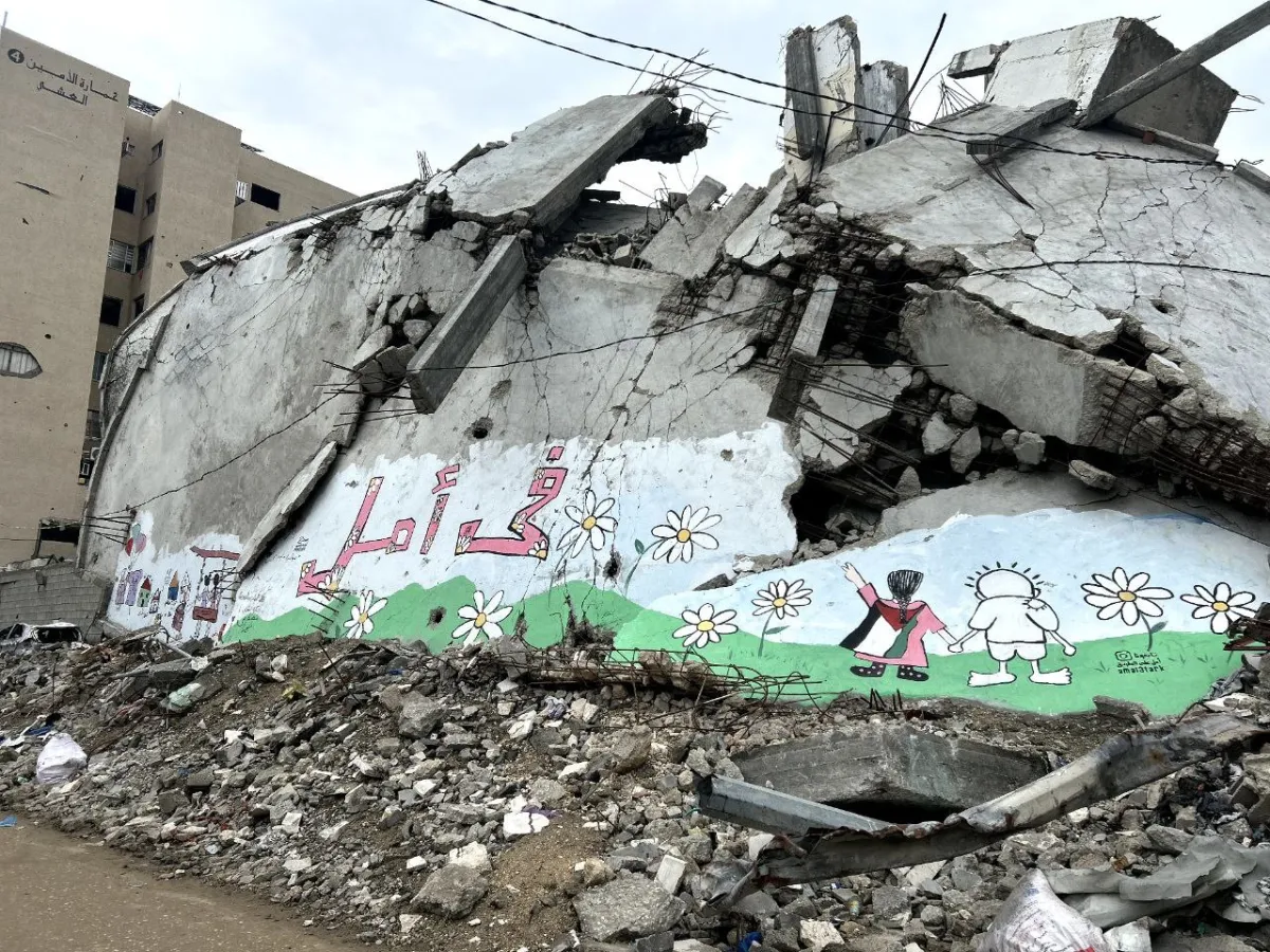 A mural painted on the rubble of a destroyed building in Al Thawra Street in Rimal, Gaza. The mural was created by Mostafa Mehna with 25 children from Gaza. The Arabic text reads "There is hope".