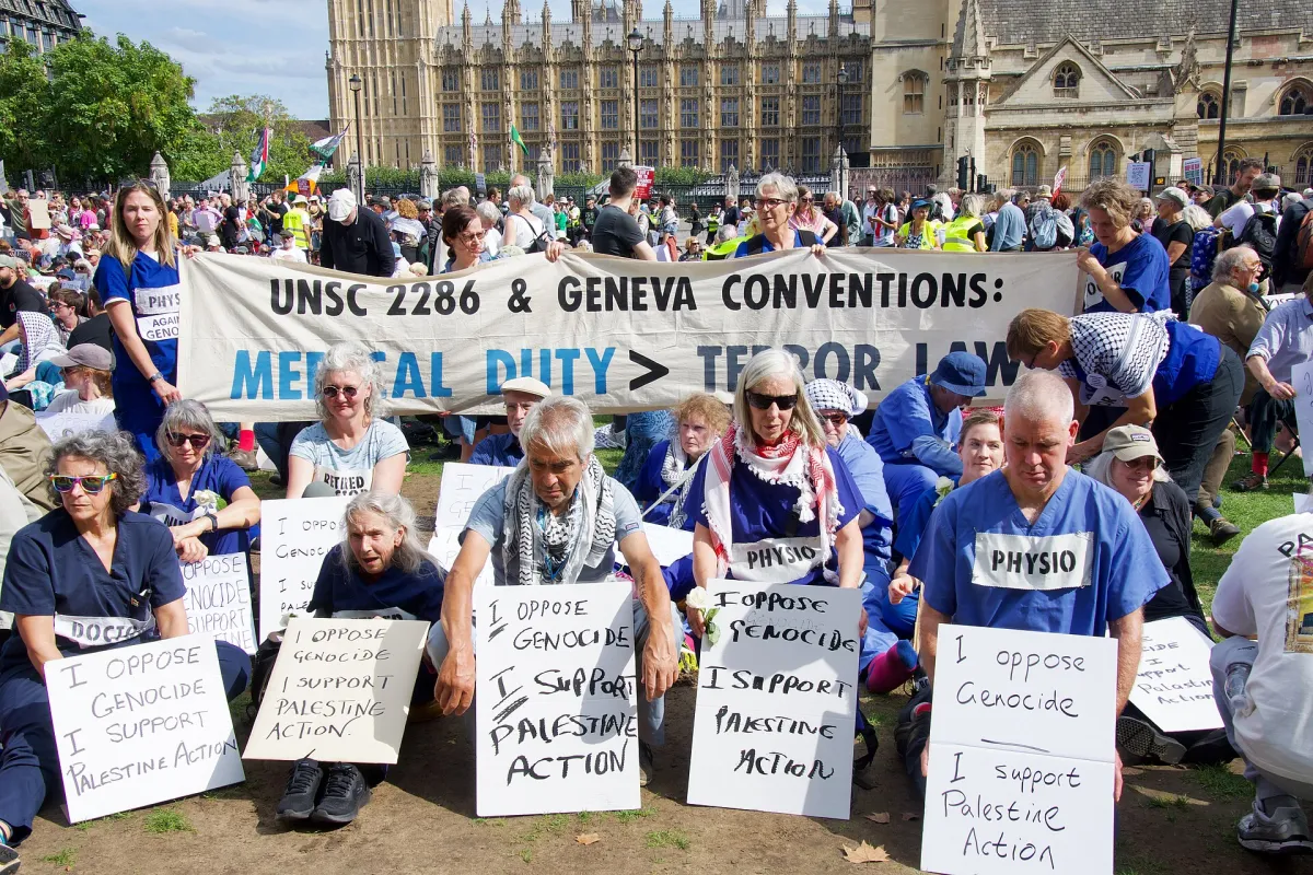 People hold signs supporting Palestine Action at a Defend Our Juries protest in Parliament Square, London, September 2025